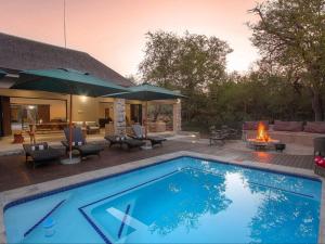 una piscina frente a una casa con chimenea en The Den at Kruger 3479 en Marloth Park