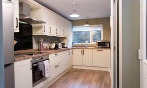a kitchen with white cabinets and a sink at Noble Cottage in Keswick