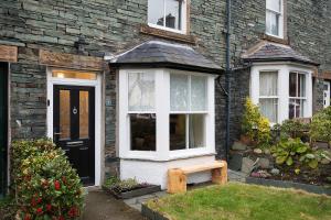 a stone house with a black door and a bench at Noble Cottage in Keswick