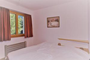 a bedroom with a white bed and two windows at Carpe Diem 2 in Fiesch