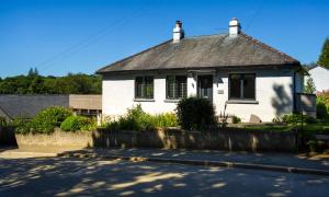 a white house with a black roof on a street at Foxrock in Windermere