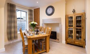 a dining room with a table and chairs and a clock on the wall at Dovedale in Keswick