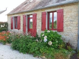 ein Steinhaus mit roten Fensterläden und Blumen in der Unterkunft Les chambres de Marie in Le Saint