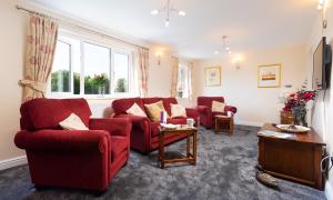 a living room with red chairs and a table at Woodside West in Bowness-on-Windermere