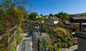a garden with a fence and a stone wall at Corner Cottage in Troutbeck