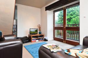 a living room with a leather couch and a television at A River Runs By in Staveley