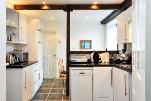 a kitchen with white cabinets and black counter tops at A River Runs By in Staveley