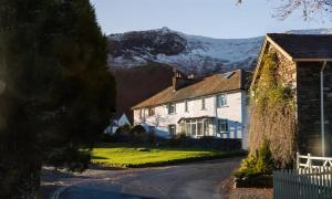 a large white house with mountains in the background at Grange Fell Borrowdale in Keswick