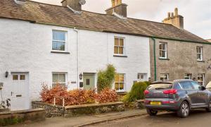 une voiture garée devant une maison blanche dans l'établissement Mulberry Cottage, à Kendal