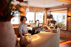 a woman sitting at a counter in a room at Hotel Auriga in Lech am Arlberg