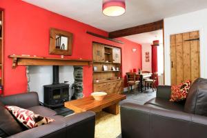 a living room with a red wall with a fireplace at Stone Cottage at Staveley in Windermere
