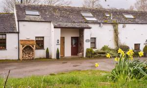 a white house with yellow flowers in front of it at Barn Cottage in Cockermouth