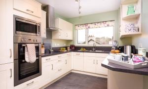 uma cozinha com armários brancos e electrodomésticos pretos em Bow Peak em Bowness-on-Windermere