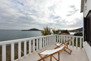 a white chair sitting on a balcony overlooking the water at Home with a unique view in Preko