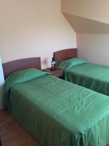 2 camas en una habitación con sábanas verdes en Hostal Brisas del Sur, en Temuco