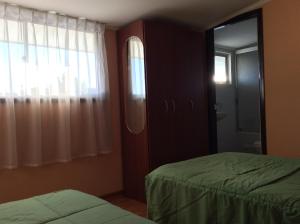 1 dormitorio con 2 camas, ventana y espejo en Hostal Brisas del Sur, en Temuco