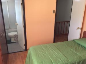 1 dormitorio con cama, aseo y espejo en Hostal Brisas del Sur, en Temuco