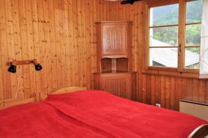 a bedroom with a red bed and a window at Melchior in Fiesch