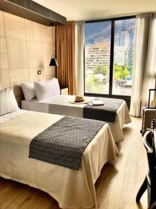 a hotel room with two beds and a large window at RQ Santa Magdalena in Santiago
