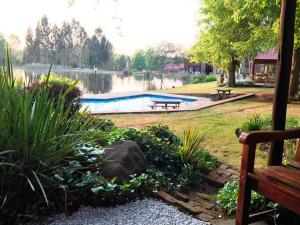 a park with a swimming pool and a bench at Lakeside Chalets Critchley Hackle Lodge in Dullstroom