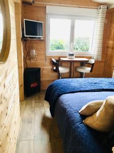 een slaapkamer met een bed, een bureau en een televisie bij La Villa plein vent "La Cabine" vue mer in Barneville-Carteret