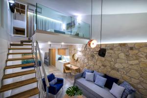 sala de estar con escalera y pared de piedra en Mary Hotel & Mary Royal Suites en Platanes