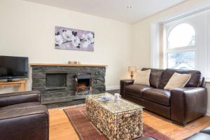 a living room with a leather couch and a fireplace at Lake Road Apartment Keswick in Keswick