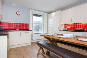 a kitchen with white cabinets and a wooden table at Lake Road Apartment Keswick in Keswick +4 photos