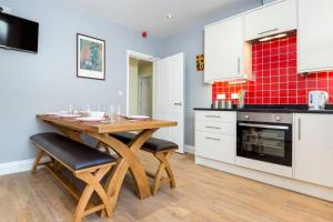 Il comprend une cuisine avec une table et des chaises en bois. dans l'établissement Lake Road Apartment Keswick, à Keswick