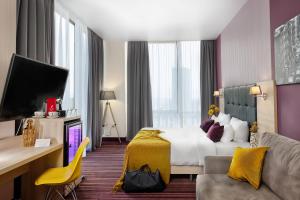 a hotel room with a bed and a tv at Golden Tulip Krasnodar in Krasnodar