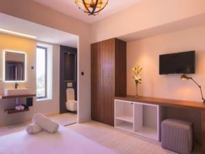 a bathroom with a toilet and a tv on the wall at Azure Beach Boutique Hotel in Grand-Baie