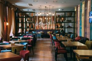 ein Restaurant mit Tischen und Stühlen und einem Kronleuchter in der Unterkunft Optima Collection Khmelnytskyi in Chmelnyzkyj