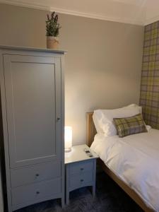 a bedroom with a bed and a dresser with a lamp at Pergola Cottage in Melrose