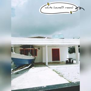 a house with a boat on the front of it at Pandai dickson Banglow white & yellow house in Port Dickson