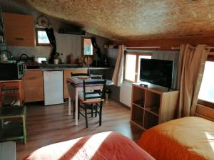 a room with a kitchen and a table with a television at les 2 studios indépendants du clos de l'Ange in Rieux