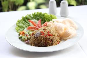 un plato de comida con piña y ensalada en Grand Ciwareng Inn Hotel and Resort, en Pasarsenen