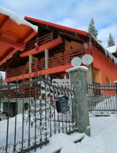 a fence in front of a house with snow at Casa de vacanța in Paraul Rece