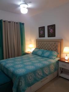 a bedroom with a bed with blue sheets and two lamps at Tropical Beach Bayahibe in Bayahibe