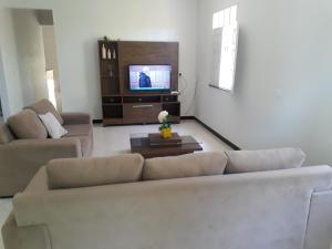 a living room with a couch and a tv at Casa de Temporada Guaibim in Guaibim
