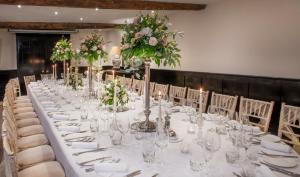 a long table with glasses and flowers on it at Macdonald Bear Hotel in Woodstock