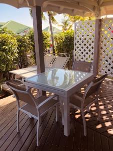 a table and chairs on a deck with an umbrella at TI-MANGO VUE MER in Sainte-Anne