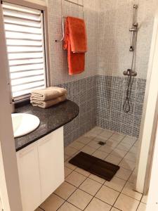 a bathroom with a sink and a shower with orange towels at TI-MANGO VUE MER in Sainte-Anne