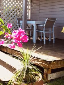 a table and chairs on a porch with pink flowers at TI-MANGO VUE MER in Sainte-Anne