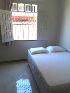 a bed in a room with a large window at Casa de Temporada Guaibim in Guaibim