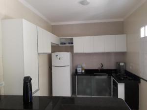 a kitchen with white cabinets and a white refrigerator at Casa de Temporada Guaibim in Guaibim