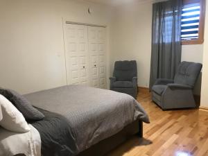 1 dormitorio con 2 sillas y 1 cama en relais chez rosa logement intime et privé, en Montmagny