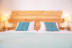 a bed with two blue and white pillows on it at Surfescape Fuerteventura in Lajares