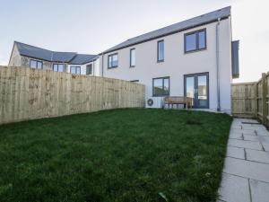 a white house with a fence and a yard at The Sand Dunes in Crantock