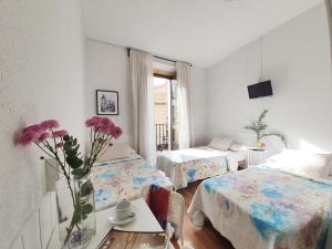 una habitación con 2 camas y una mesa con flores en Hostal Alicante, en Madrid