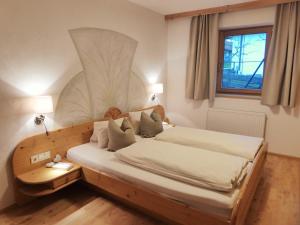 - une chambre avec un lit et une tête de lit en bois dans l'établissement Alpbacher Appartementhaus Johannes, à Alpbach